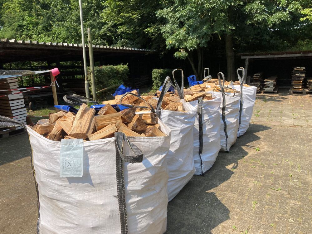 een rij big bags met blokken haardhout staat klaar om te vervoeren
